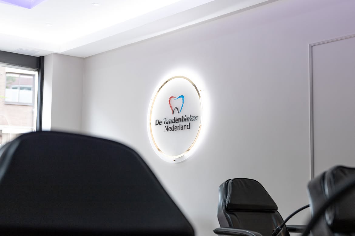 Interieur van een De Tandenbleker Nederland studio met verlicht merkbord en zwarte behandelsstoelen